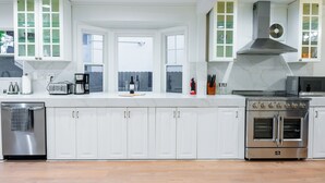 A modern kitchen with white cabinetry, a built-in oven, and a large window. - Palo Alto Villa (East Palo Alto)