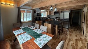 A spacious kitchen with wooden beams, a dining area with a large table, and a refrigerator. - 30 Mins from YNP -Trail Access-Three Little Bears (Island Park)