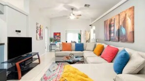 A modern living room with a sofa, TV, and artwork on the wall. - Hidden Gem in La Quinta Cove with saltwater pool and spa, close to old town LQ (La Quinta)