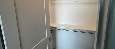 Un petit placard fermé, doté d’une porte, d’une étagère et d’une tringle pour suspendre les vêtements.