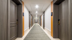 A long, narrow hallway with wooden doors on both sides, a carpeted floor, and a ceiling with recessed lighting. - AI Lives In The Future Hotel(Xi'an Longshouyuan Daming Palace West Subway Station Branch) (Xi'an)