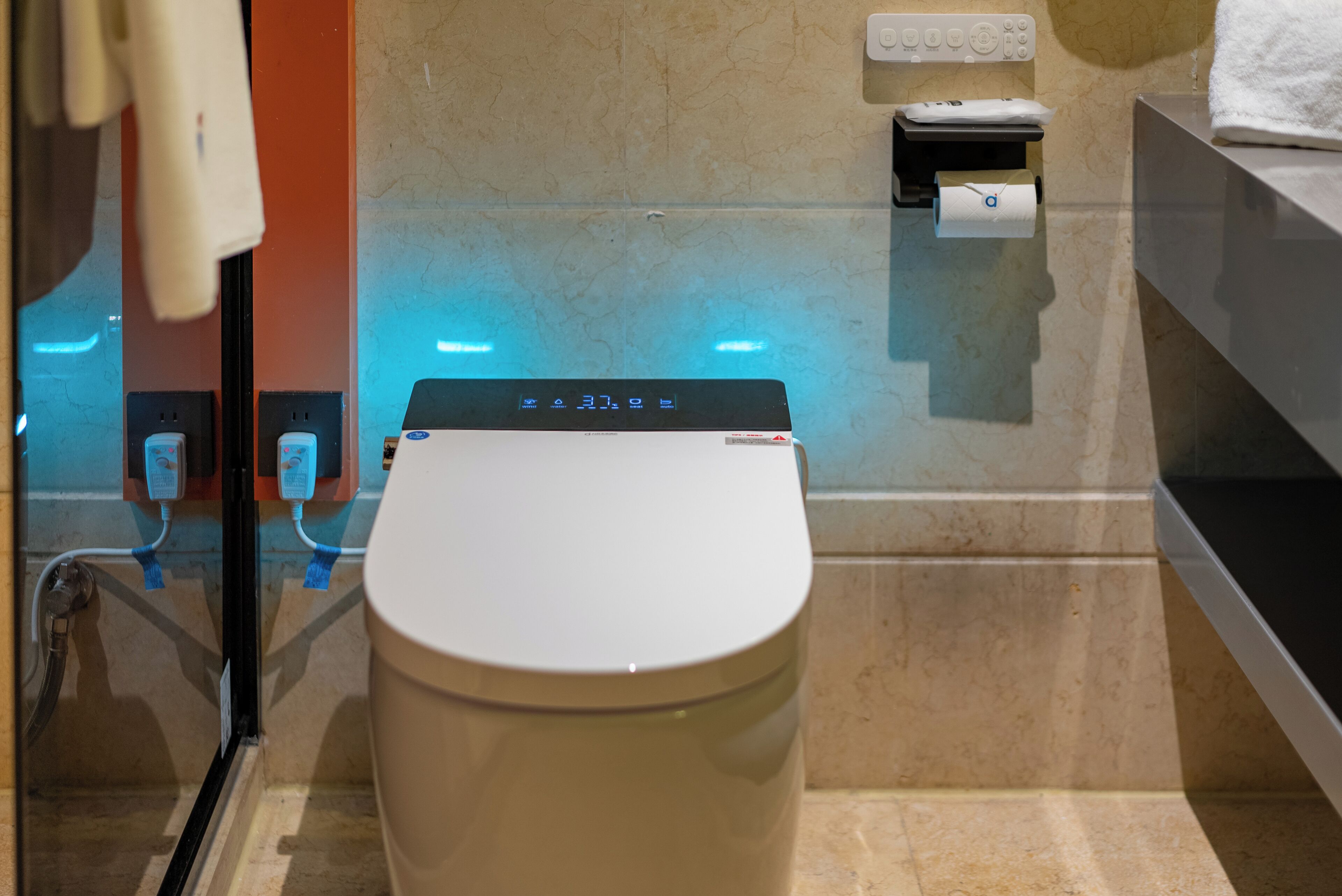Ein modernes Badezimmer mit Toilette, Handtrockner und Papierhandtuchspender.