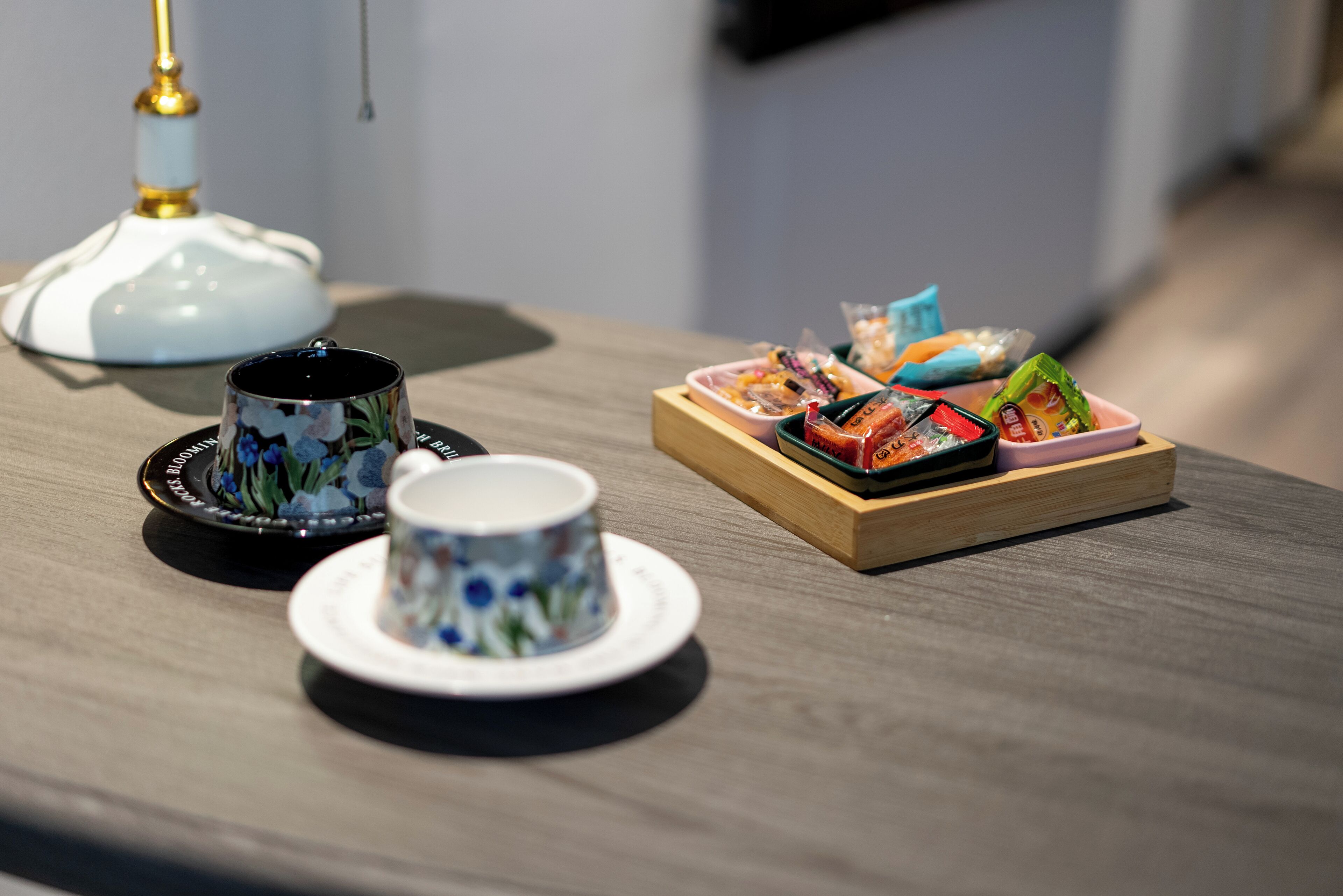 A table with a teapot, cups, and a tray of snacks.