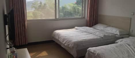 Una habitación con dos camas, un escritorio de madera y una ventana con cortinas.