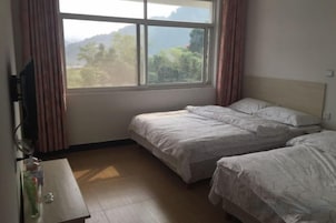 Una habitación con dos camas, un escritorio de madera y una ventana con cortinas.