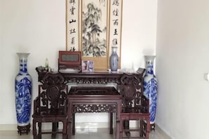 A traditional Chinese room with a wooden table, two blue vases, and calligraphy scrolls.