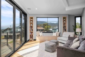 A modern living room with a large window, a sofa, a coffee table, and built-in bookshelves.