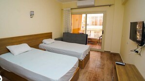 A hotel room with two single beds, a TV, and a sliding glass door to a balcony. - Florenze Khamsin Hurghada- - Room K203 (Hurghada 1)