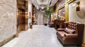 A spacious hallway with marble flooring, a leather armchair, and a potted plant. - James Joyce Coffetel (Hefei Fortune Plaza, Haitang Metro Station) (Hefei)