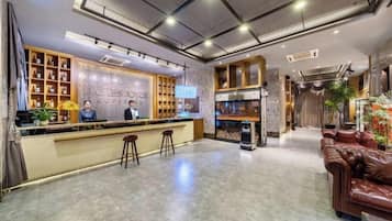 A hotel lobby with a reception desk, bar area, and seating.
