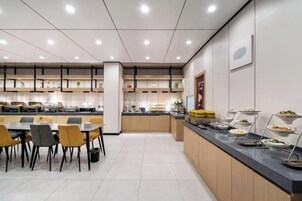 A modern cafeteria with a long counter, multiple seating areas, and a clean, organized layout.
