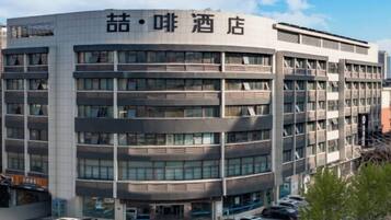 Un hôtel à plusieurs étages doté d’une architecture moderne, avec une entrée principale et un espace de stationnement situé à l’avant.