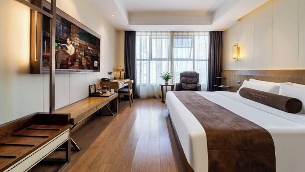 A hotel room with a large bed, a desk, a chair, a TV, and a window with curtains. - James Joyce Coffetel (Hefei Fortune Plaza, Haitang Metro Station) (Hefei)