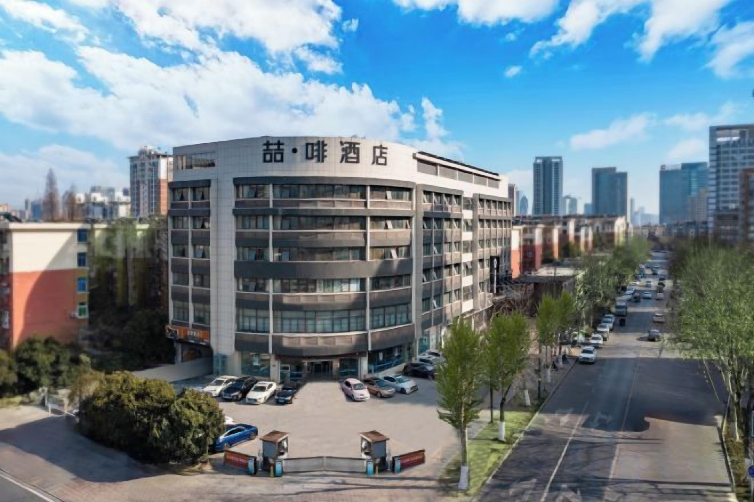 A multi-story hotel with a parking lot and a clear view of the city skyline.