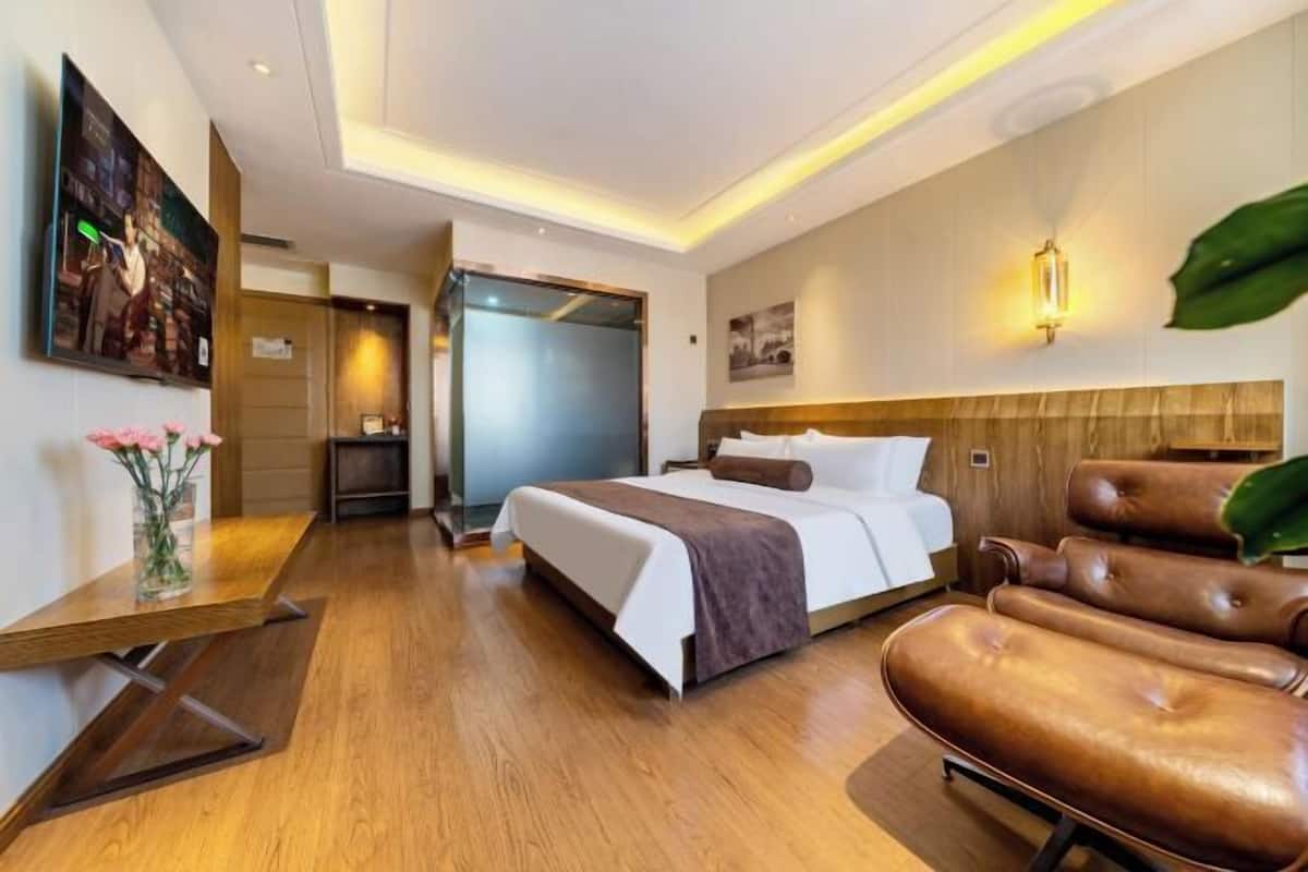 A hotel room with a bed, a desk, a chair, and a large window.