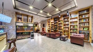 A spacious lobby with a high ceiling, a large bookshelf, comfortable seating, and a digital information board. - James Joyce Coffetel (Hefei Fortune Plaza, Haitang Metro Station) (Hefei)