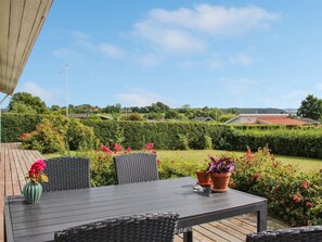 Relax in the serene outdoor patio surrounded by lush hedges and vibrant flowers, perfect for enjoying the view.