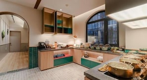 A modern kitchen with wooden cabinets, a large window, and a variety of cooking pots and utensils. - Xana Hotelle (Beijing)