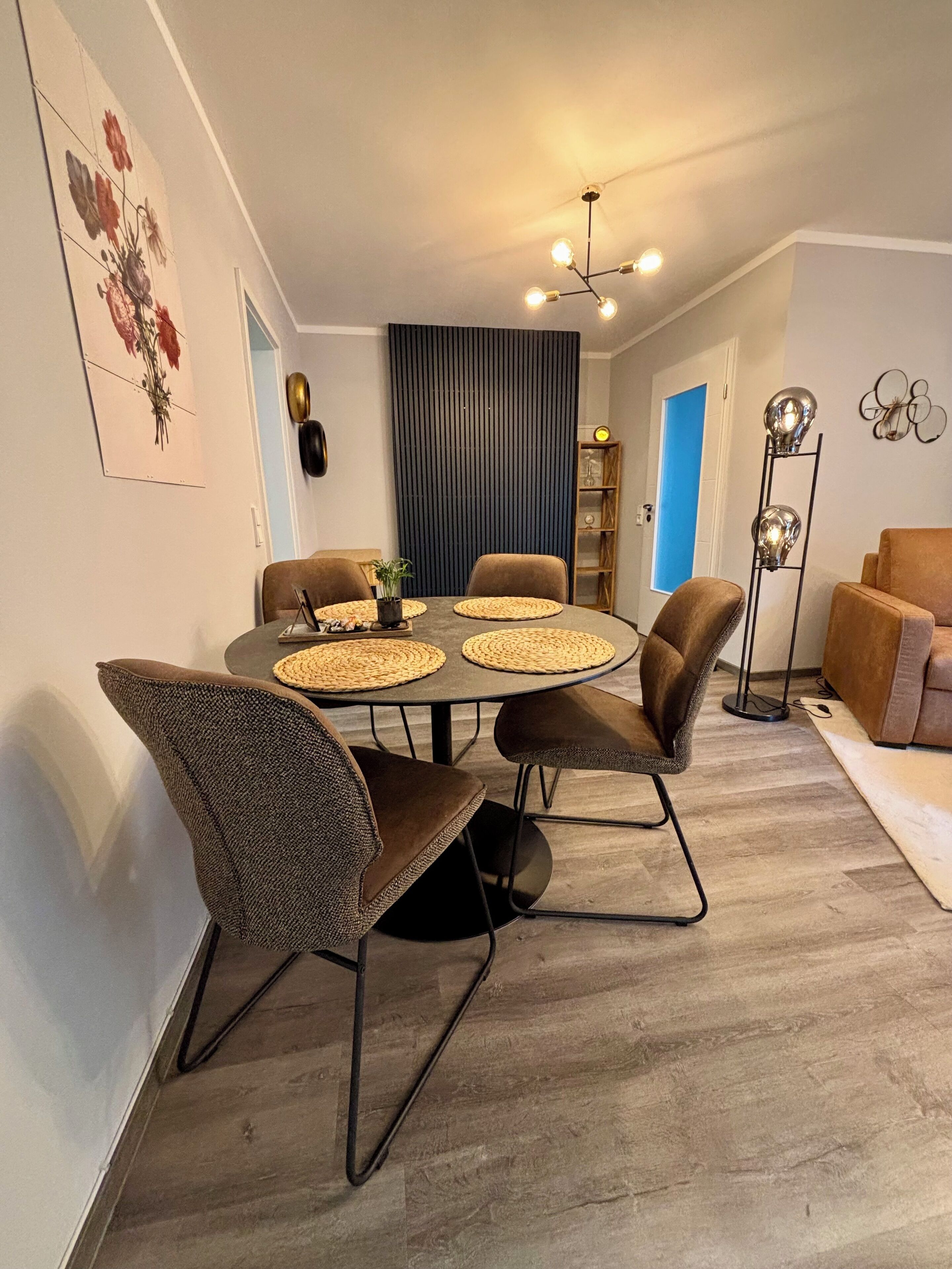 Un coin repas avec une table ronde, quatre chaises et un lustre moderne.
