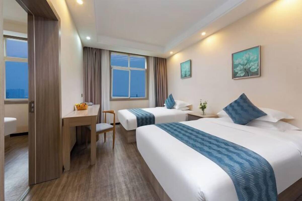 Quarto de hotel com duas camas, uma mesa e uma cadeira.