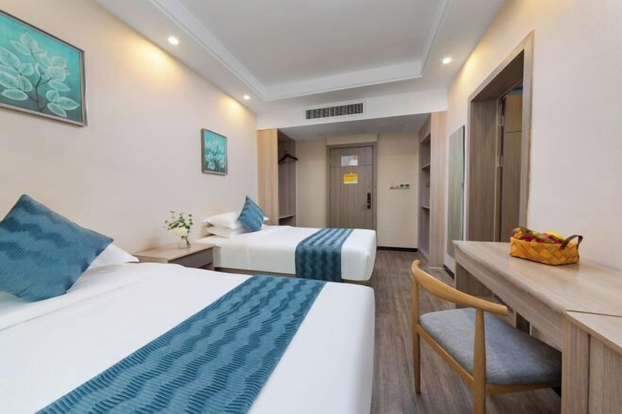 A hotel room with two beds, a desk, and a chair.
