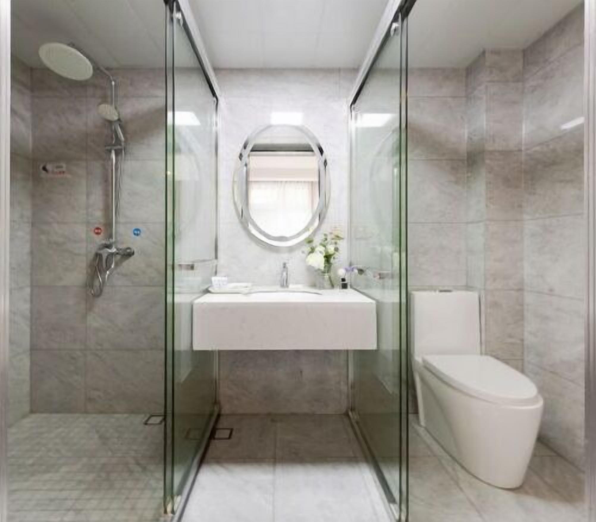 A modern bathroom with a glass-enclosed shower, a white sink, and a toilet.