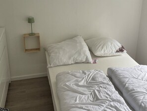 A simple, clean room with a bed, pillows, a bedside table with a lamp, and a small shelf. - "Angret" - 200m from the sea by Interhome (Haderslev)