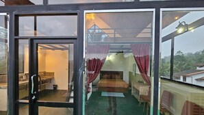 Una habitación con cama, una mesita y una silla. Hay una ventana con cortinas y vistas al exterior.