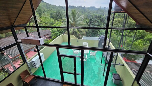 Una habitación con techos altos y grandes ventanales que dan a un espacio exterior verde con piscina y sillas.