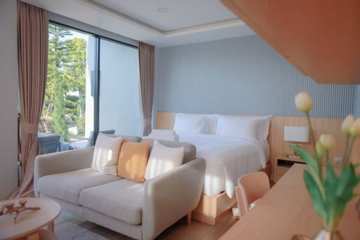 Una habitación de hotel con cama, sofá, mesita y mesita de noche.