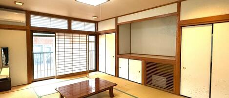 A traditional Japanese room with tatami flooring, a low wooden table, sliding doors, and a built-in shelf.