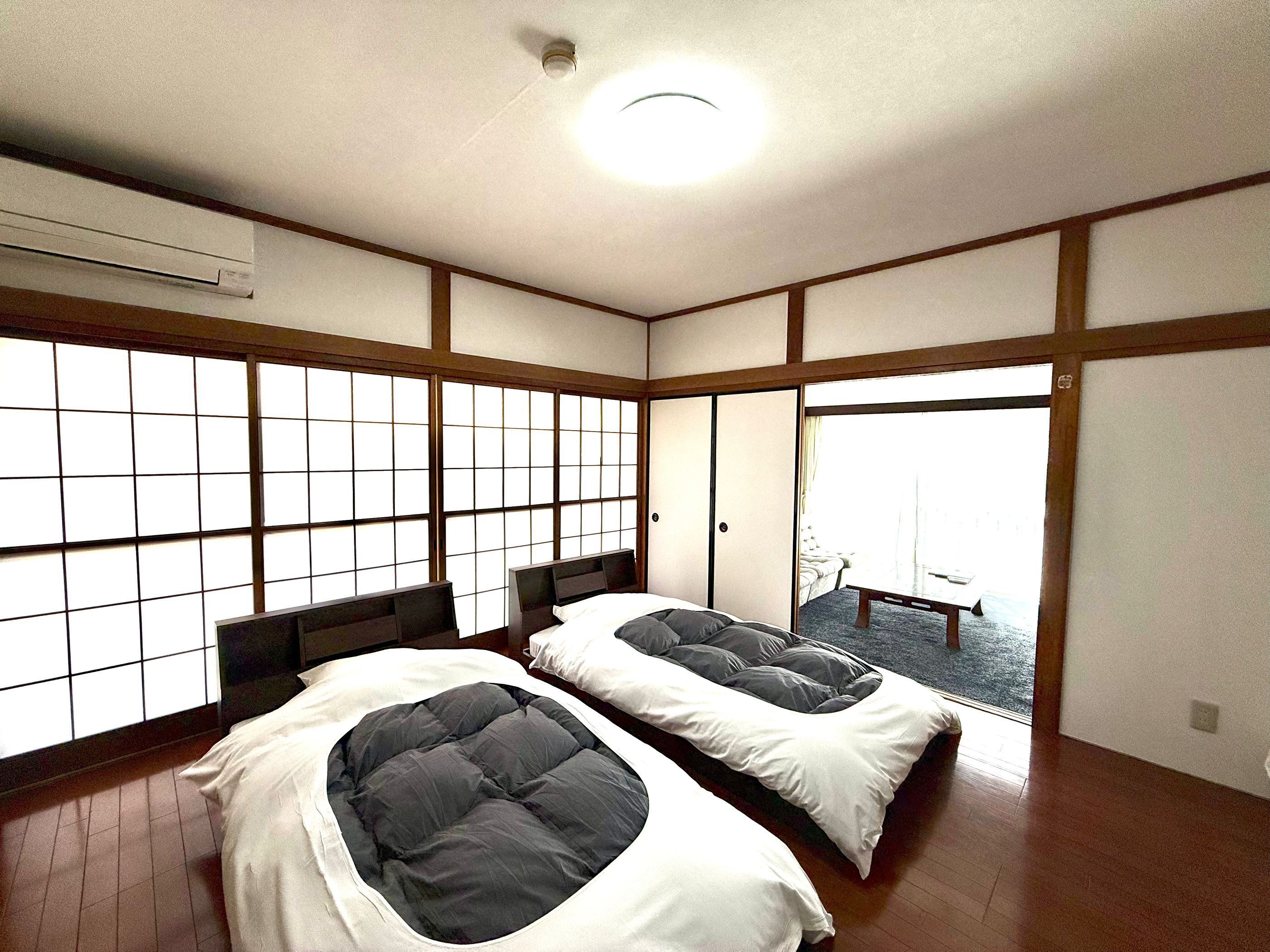 A traditional Japanese room with tatami flooring, sliding doors, and a bed with a dark mattress.