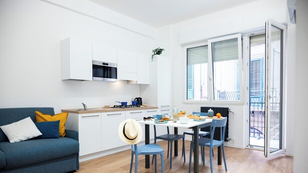 Un espacio habitable compacto con kitchenette, comedor y balcón.