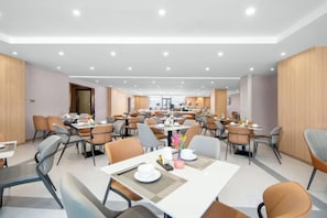 A spacious dining area with multiple tables and chairs, a central walkway, and a view of the kitchen in the background. - Vianna Hotel (Kunming)