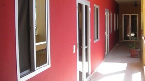 Un couloir aux murs rouges et aux fenêtres à cadre blanc.