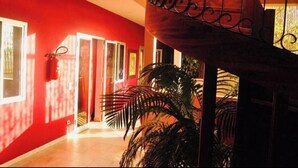 Un couloir aux murs rouges, avec un escalier en bois et un extincteur fixé au mur.