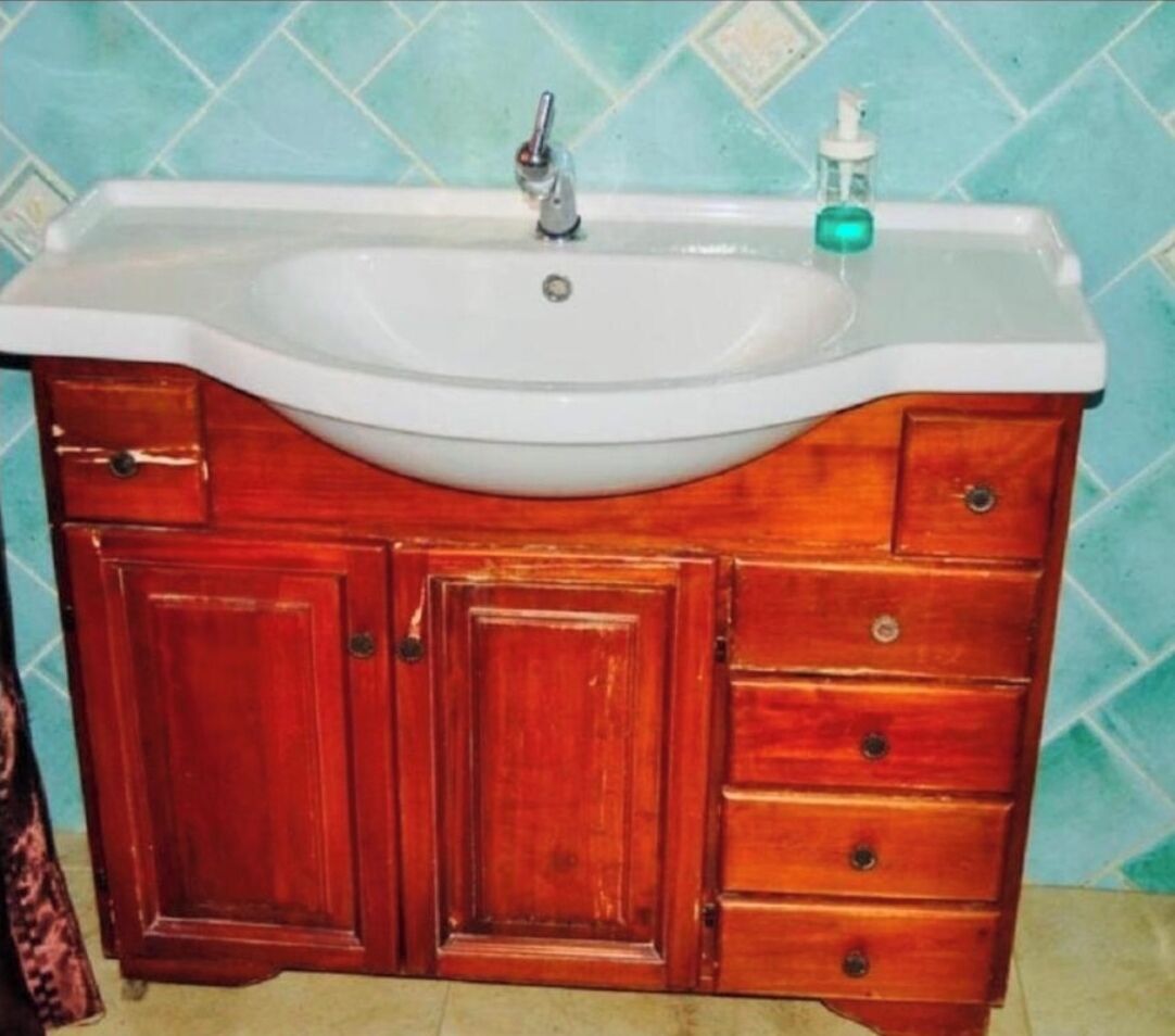 A bathroom with a white sink, wooden vanity, and a blue tiled wall.