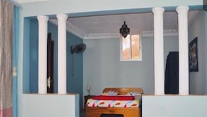 Une chambre à coucher avec un lit en bois, une fenêtre et un ventilateur de plafond.