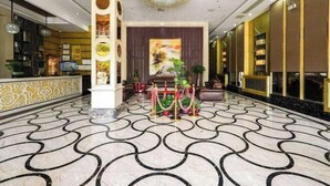 A lobby with a marble floor, a reception desk, a chandelier, and a large painting on the wall.