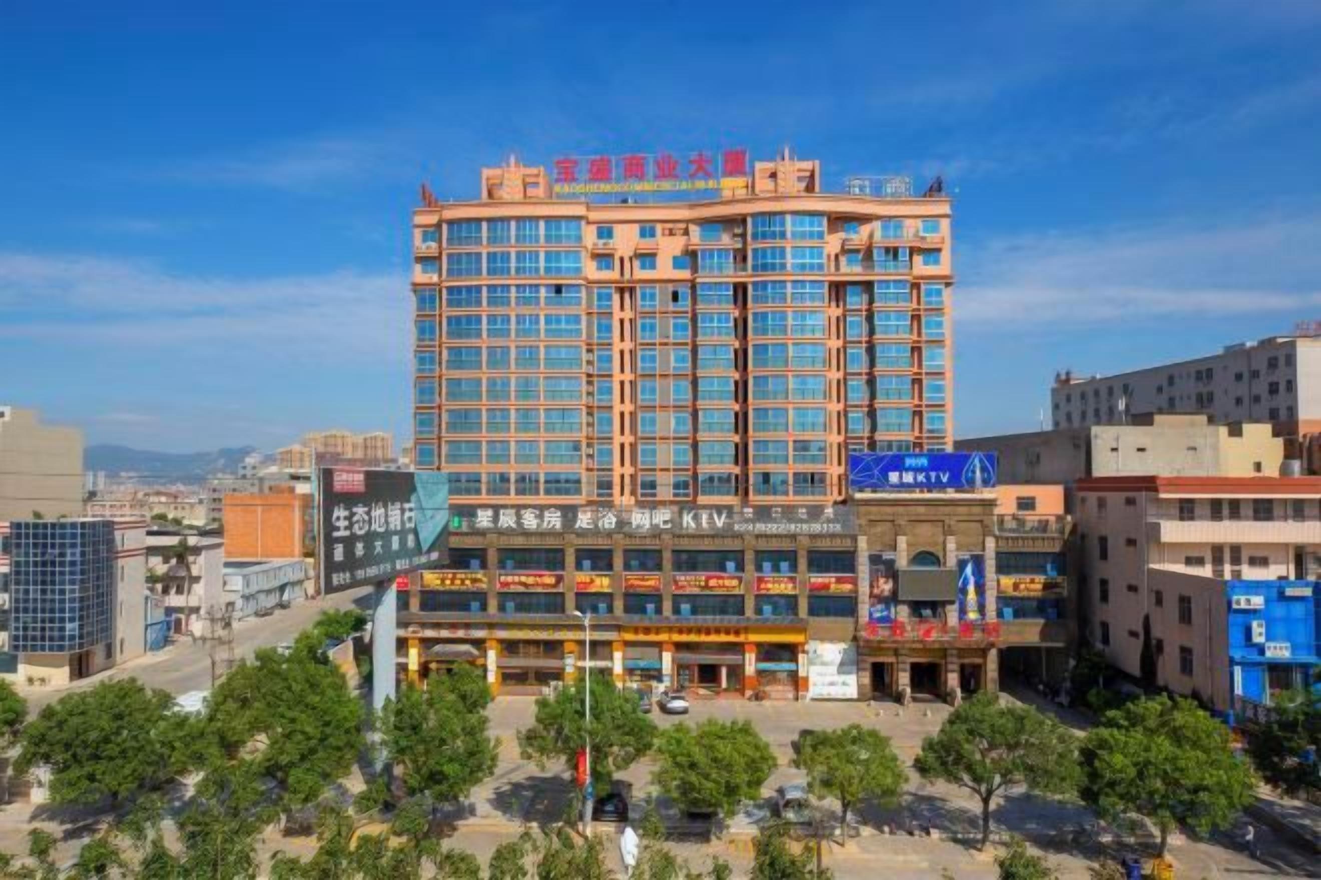 A multi-story hotel with a prominent red and blue sign, surrounded by other buildings and trees.