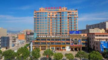 A multi-story hotel with a prominent red and blue sign, surrounded by other buildings and trees.
