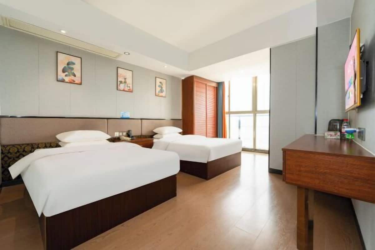 Habitación de hotel con dos camas, un escritorio y un televisor.