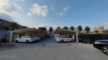 A parking area with multiple cars, covered parking structures, and a clear sky.