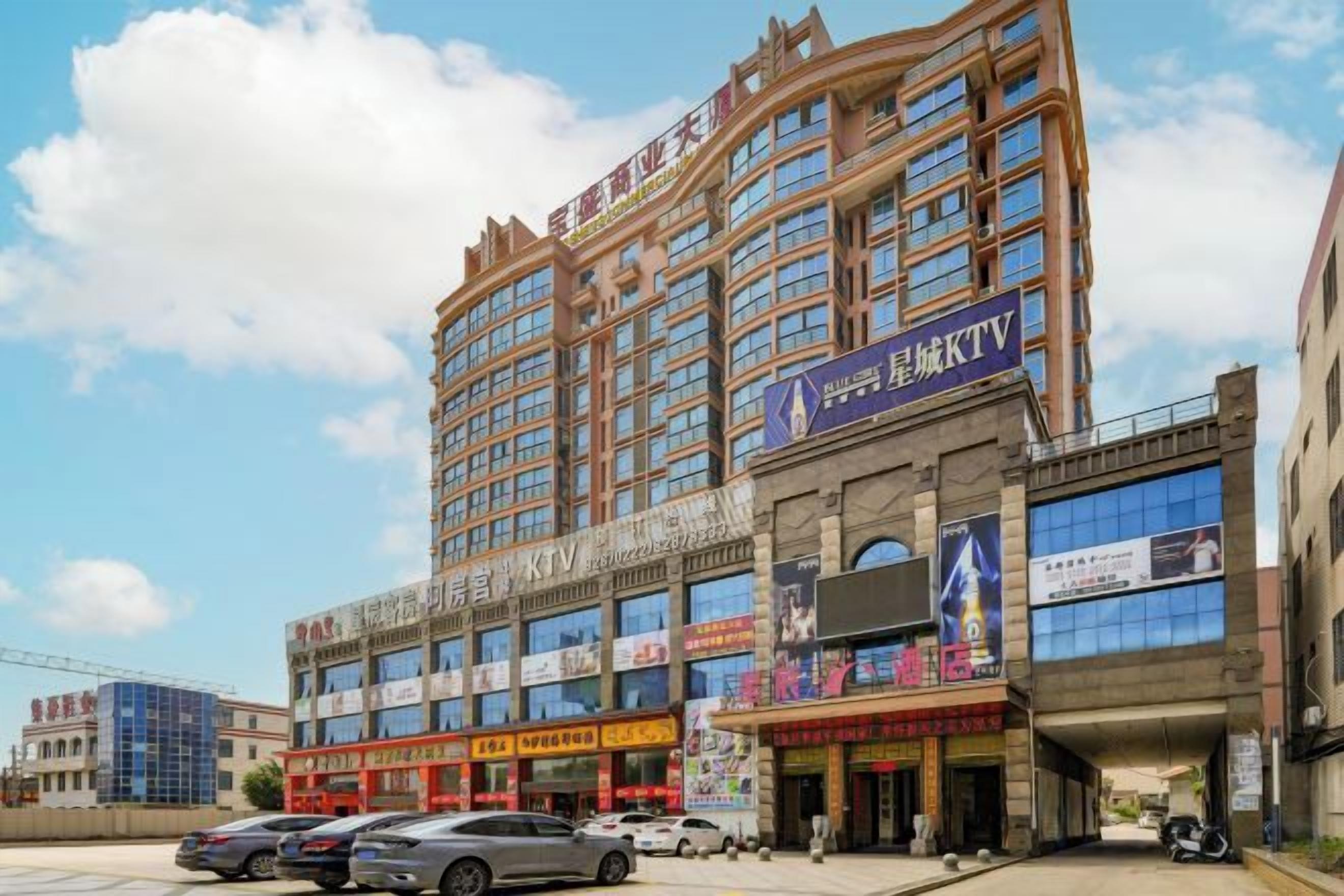 Un hotel de varios pisos con un diseño moderno, que presenta un cartel llamativo para un KTV en la planta baja.