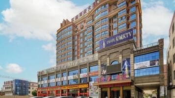 Un hotel de varios pisos con un diseño moderno, que presenta un cartel llamativo para un KTV en la planta baja.