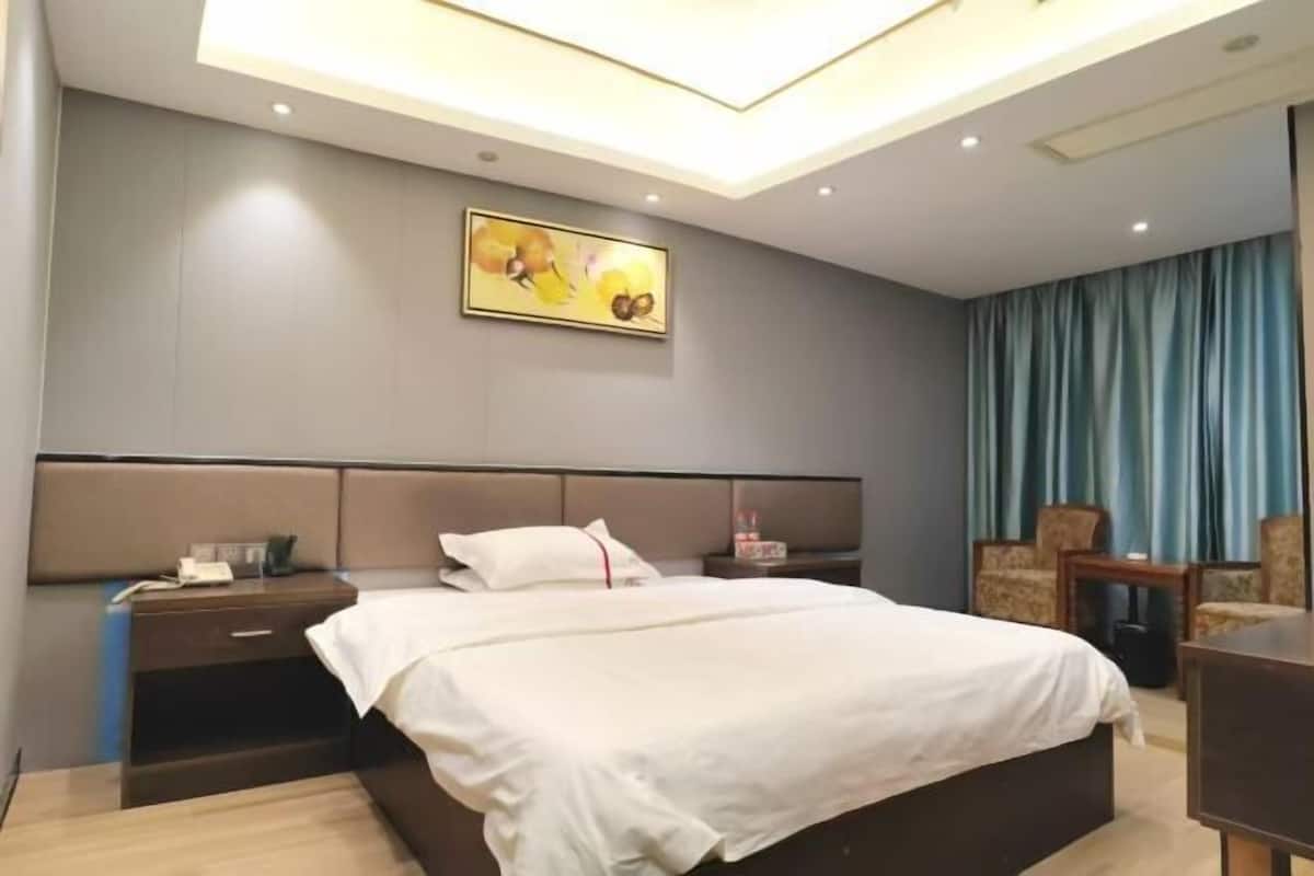 Habitación de hotel con una cama grande, una mesita de noche, una silla y un cuadro en la pared.
