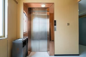 An elevator with a metallic interior, a control panel on the wall, and a trash bin to the left. - Jinjiang Star Hotel (Quanzhou Jinjiang Railway Station) (Jinjiang)