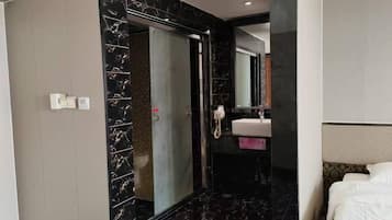 A hotel room with a bed, a bathroom with a mirror, and a sink.
