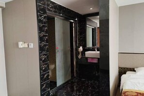 A hotel room with a bed, a bathroom with a mirror, and a sink.