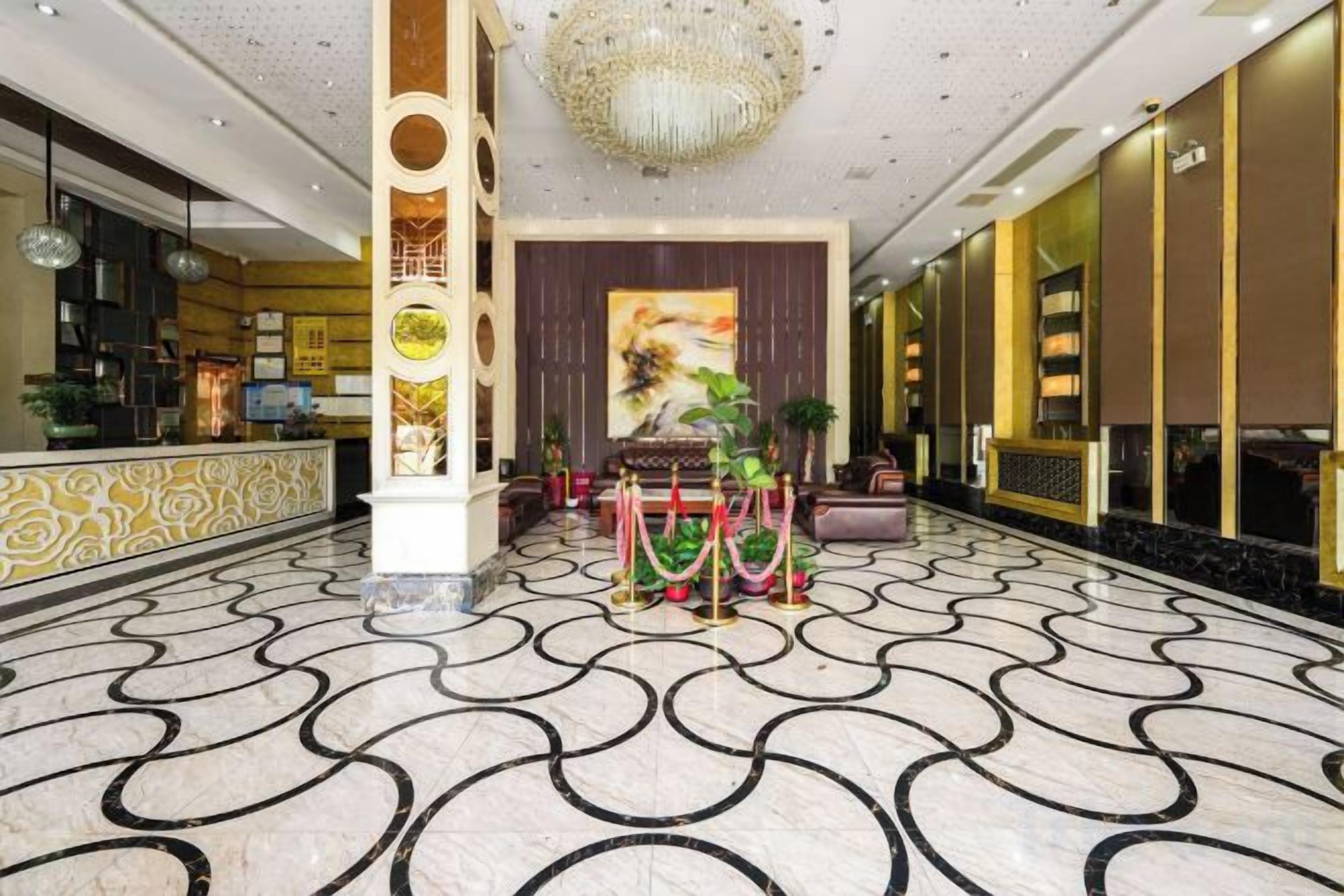 A lobby with a marble floor, a reception desk, a chandelier, and a large painting.